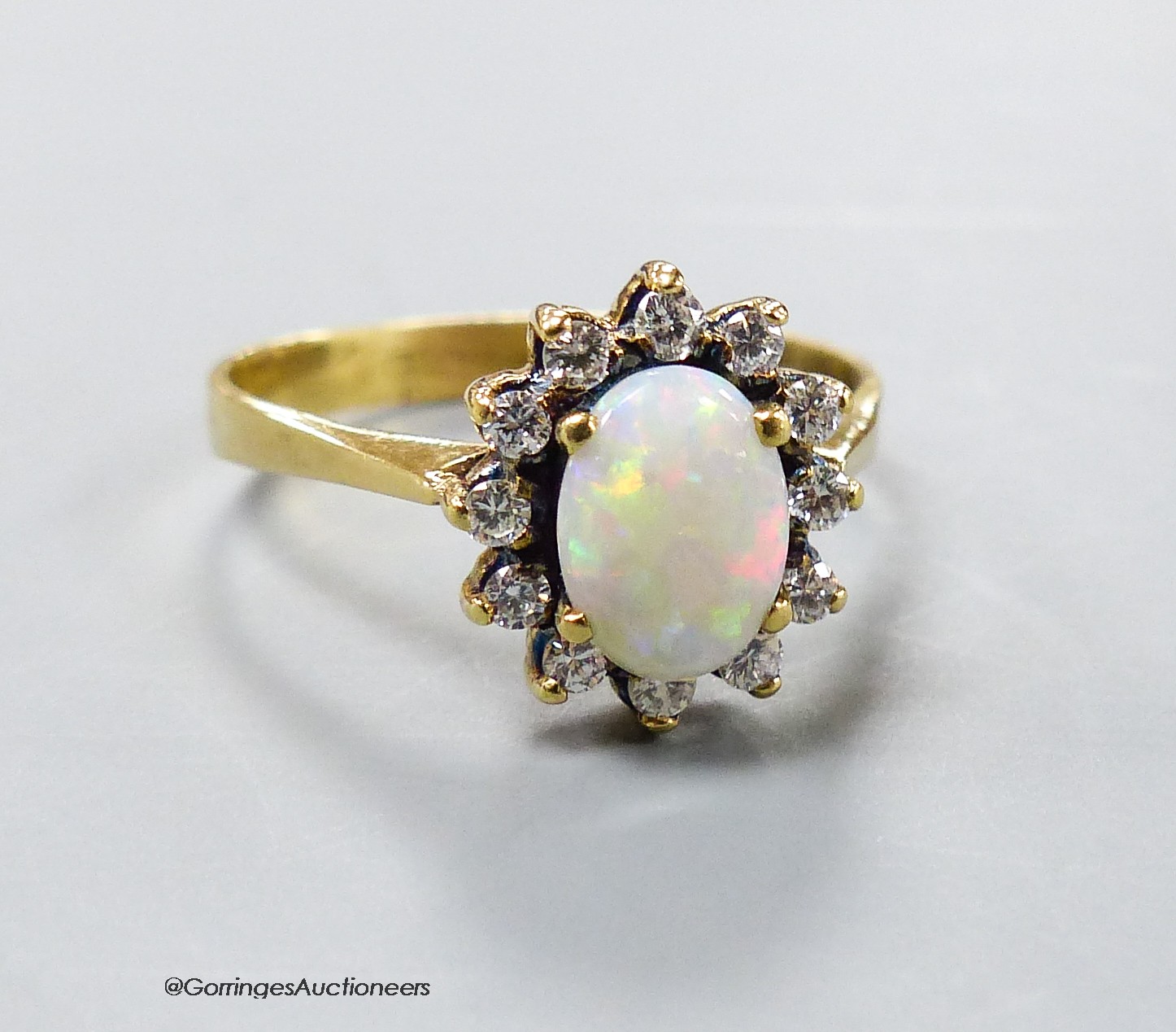 A modern yellow metal, white opal and diamond set oval cluster ring, size S, gross 4 grams.